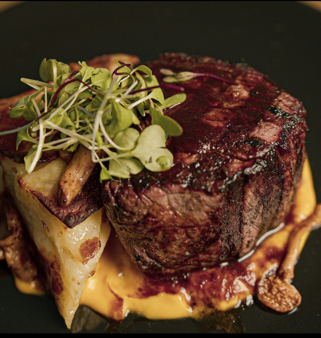 Sliced chateaubriand with herb butter on a black plate