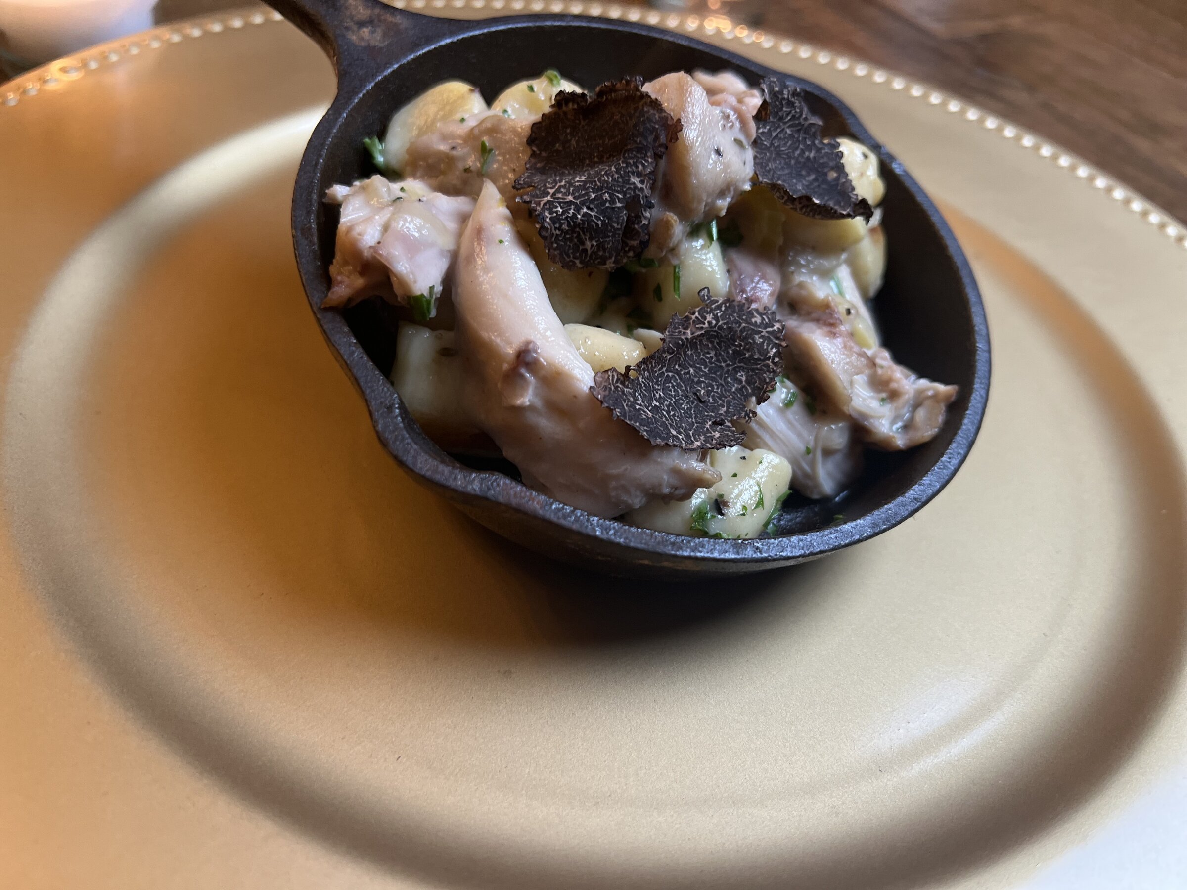 Rabbit gnocchi with black truffle shavings in a small cast iron skillet